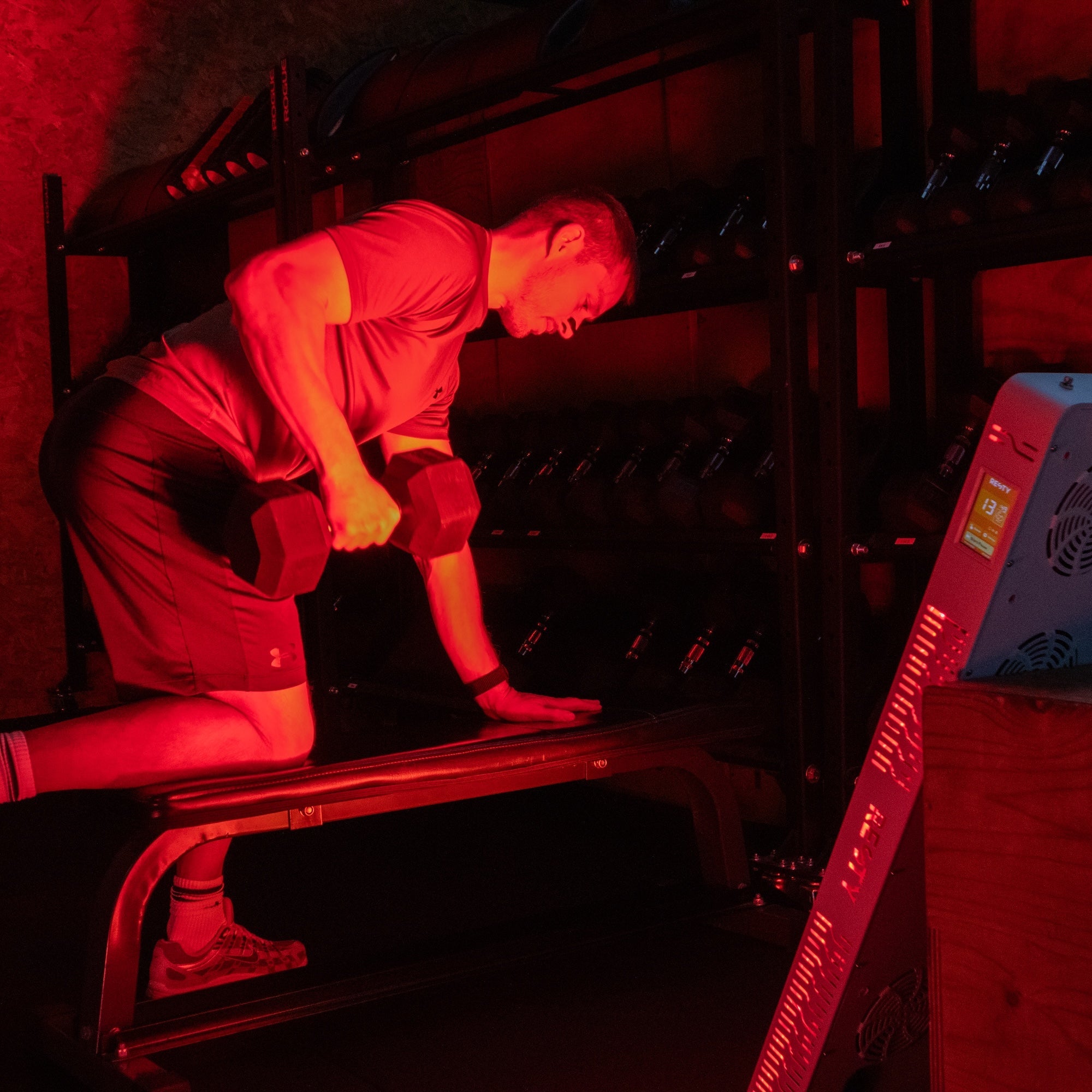 Hombre haciendo ejercicio junto al panel de luz roja Resty MARS 1200 encendido en un gimnasio