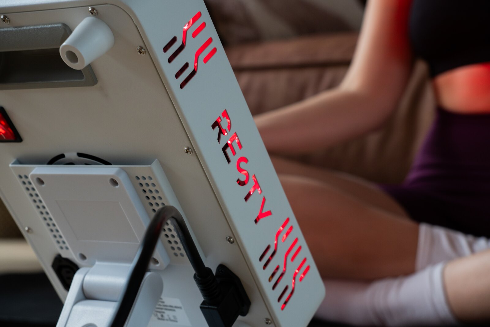 Mujer usando un panel de luz roja Resty MARS en casa