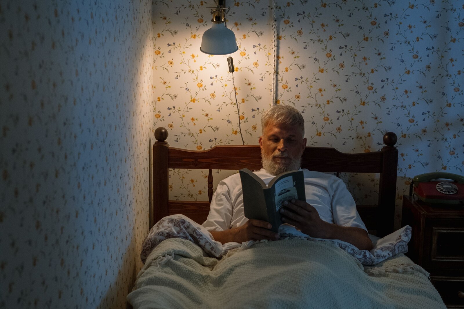 Homem mais velho a ler um livro na cama