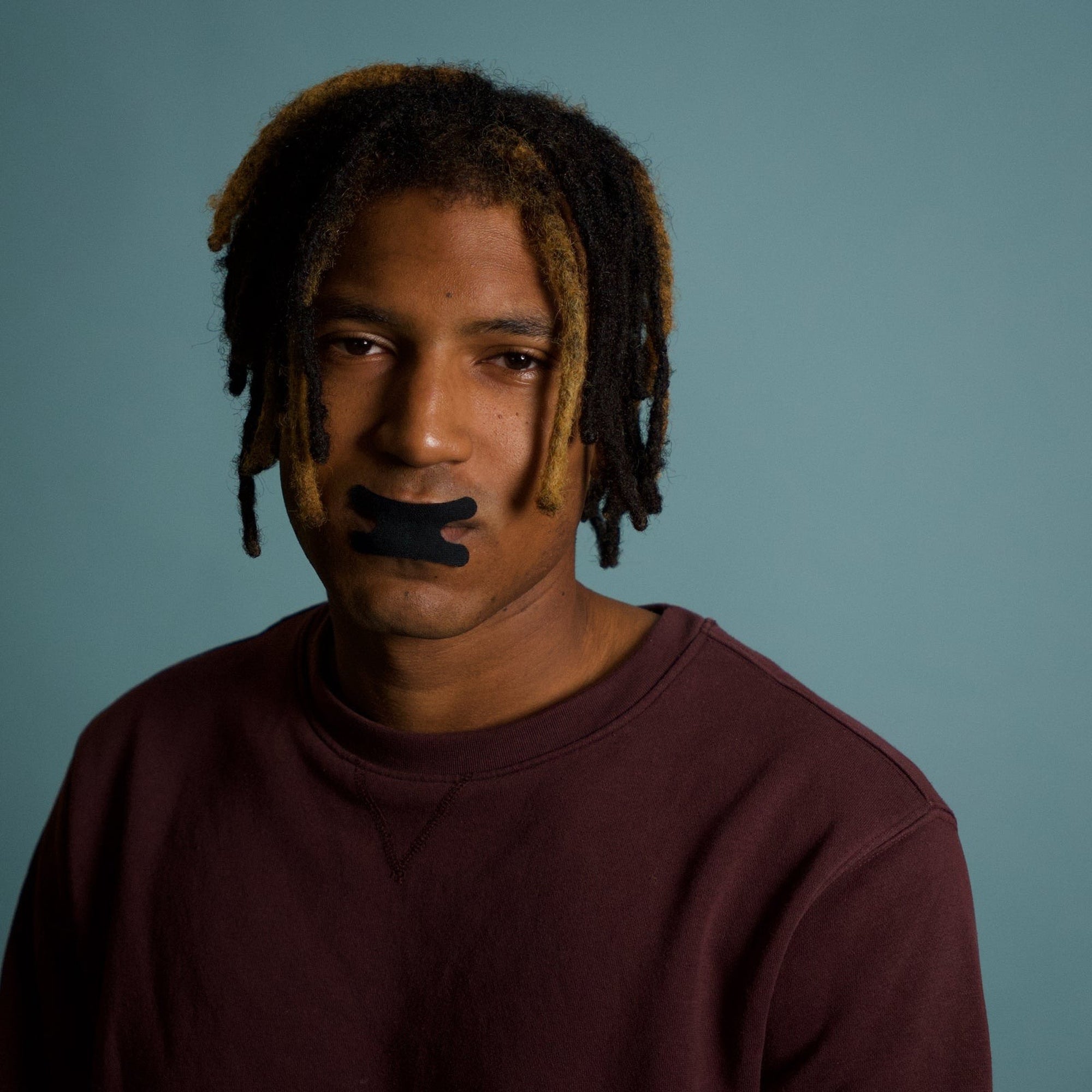 Man facing the camera with black Resty Advanced H Shape mouth tape
