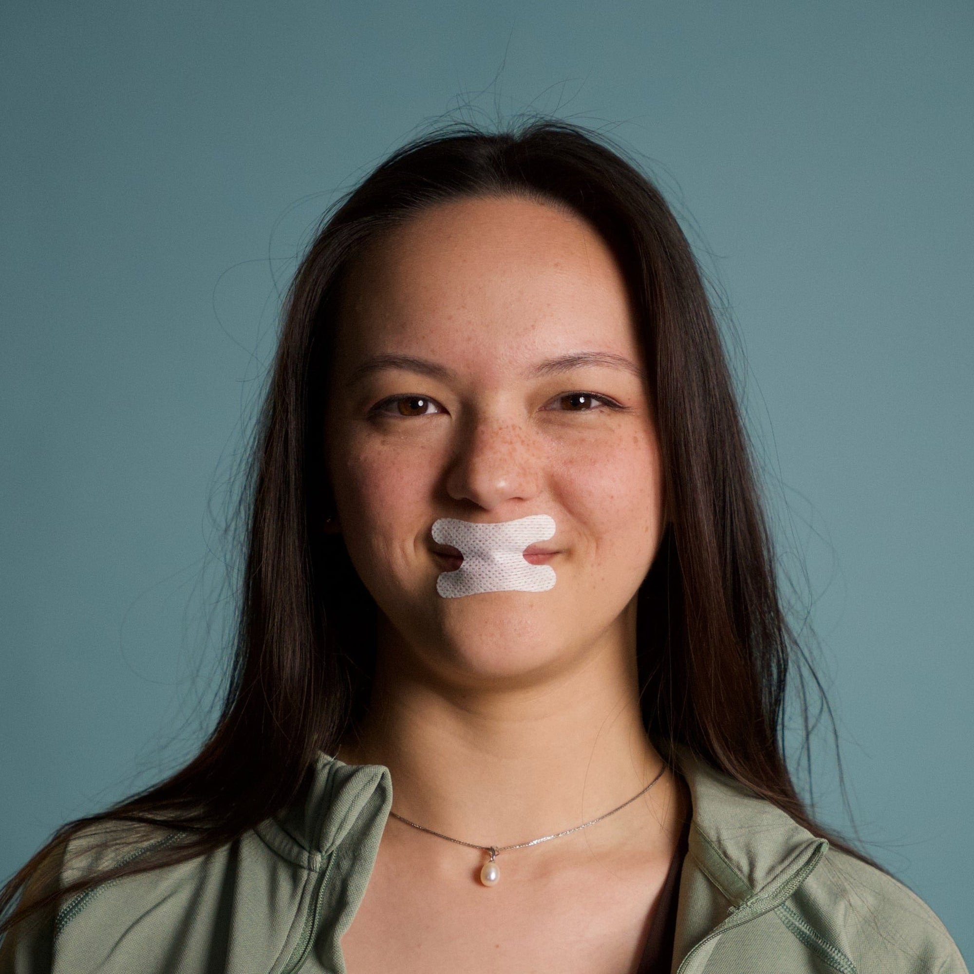 Studio portrait of a woman wearing white Resty H Shape mouth tape