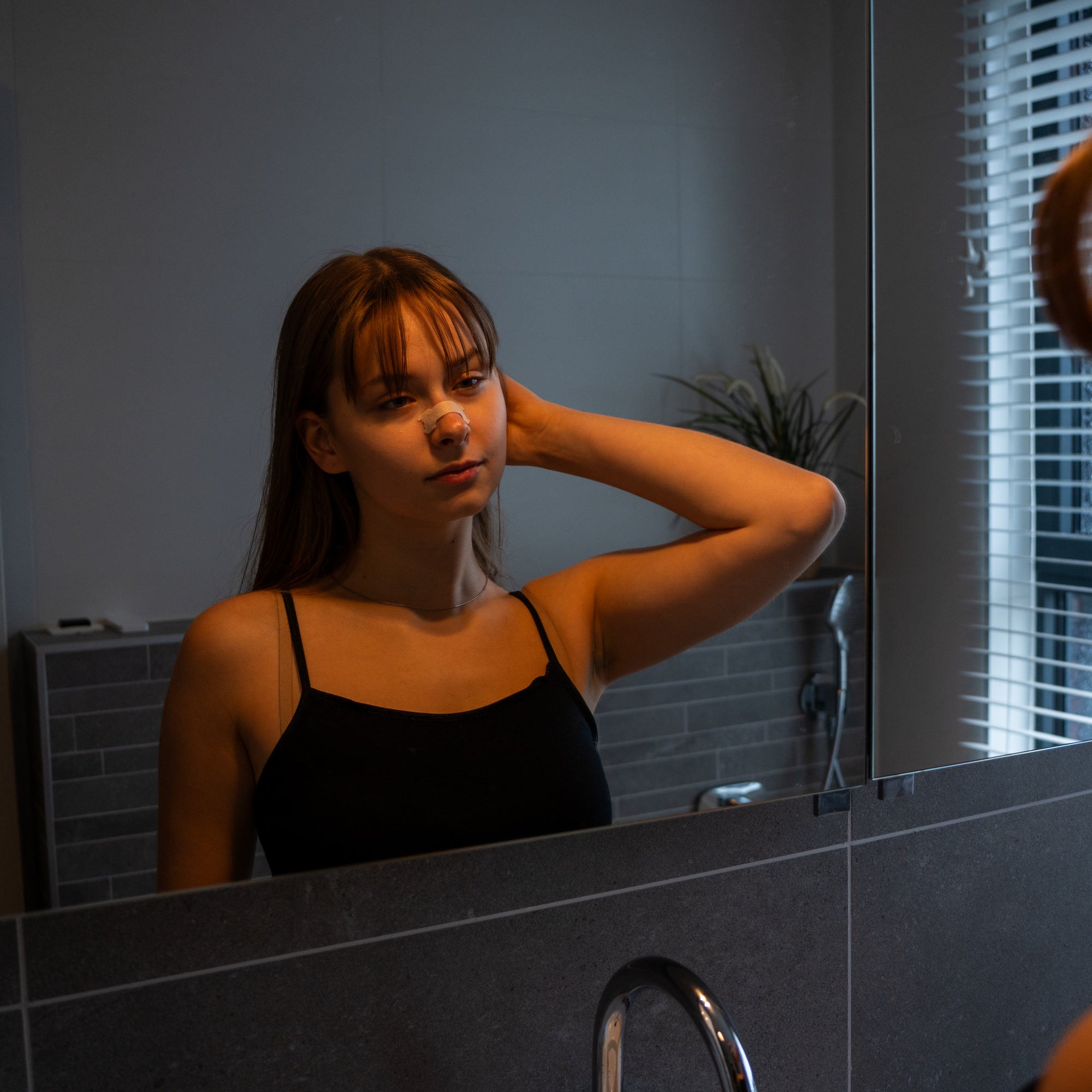 Sandy Tan Resty nasal strip worn during an evening mirror routine