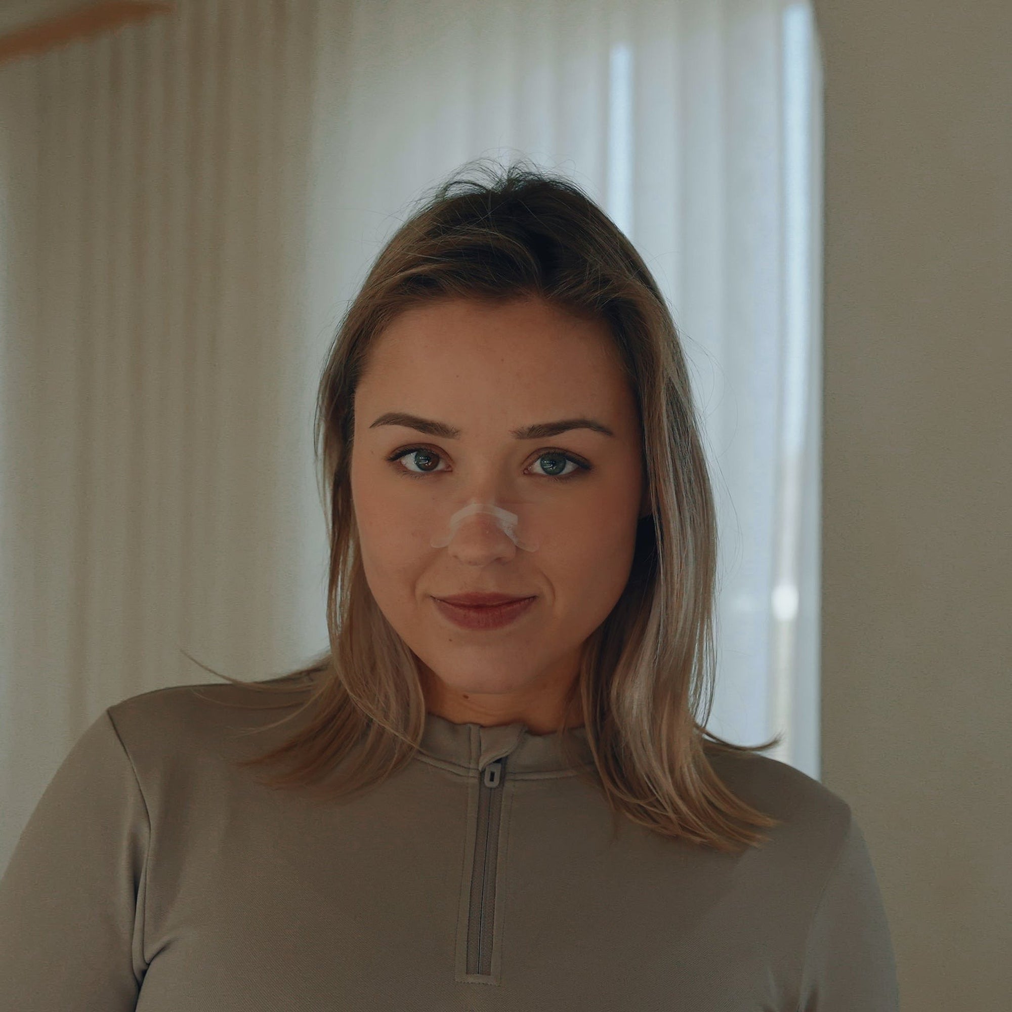 Femme vue de face avec une bandelette nasale transparente Resty sur le nez
