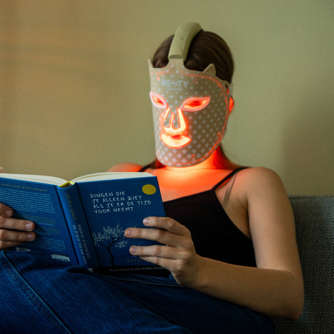 Personne utilisant le masque facial LED Resty MARS100 en lisant à la maison