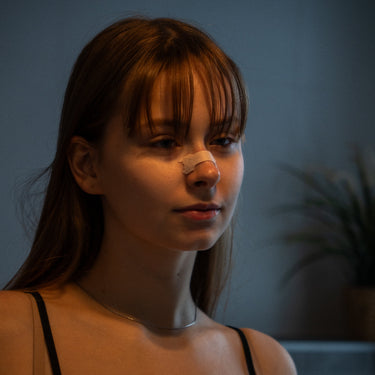Woman wearing a black tank top against a dark background