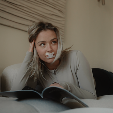 Eine blonde Frau liest ein Buch. Sie trägt ein Resty h-förmiges Mundband